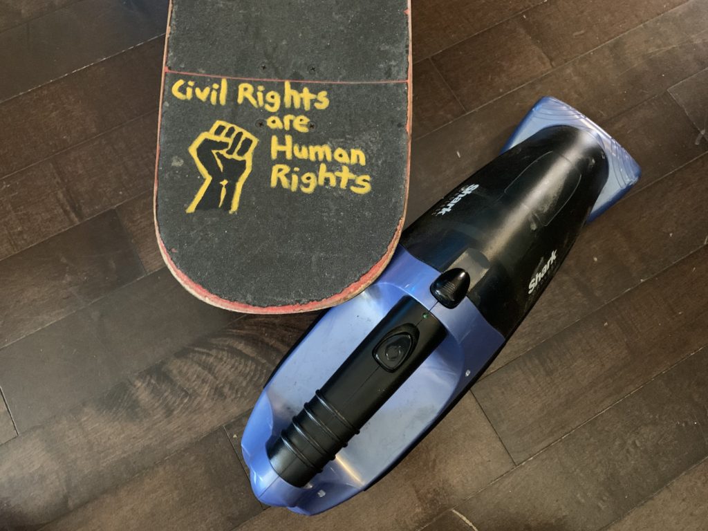 Skateboard tail with a BLM fist and the words 'Civil Rights are Human Rights' written on the griptape with yellow paint marker
